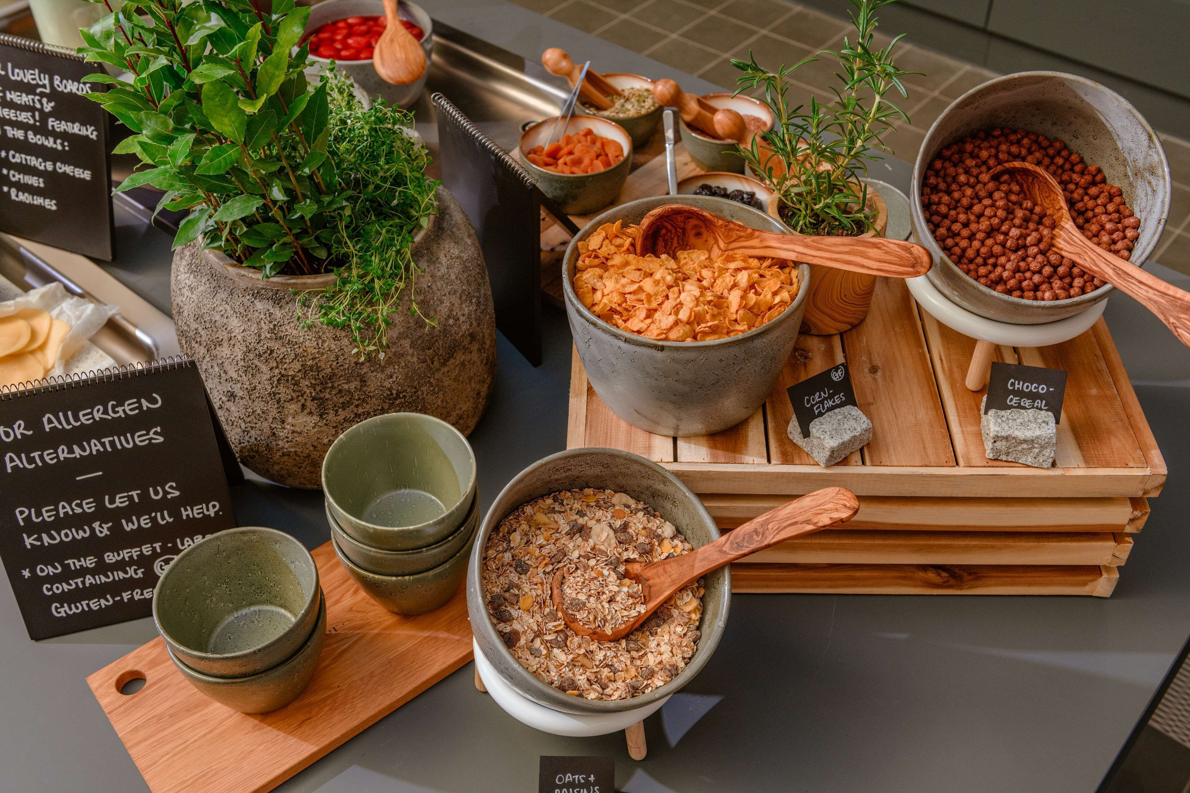A variety of food items including oats, chocolate, and other snacks displayed on wooden trays.