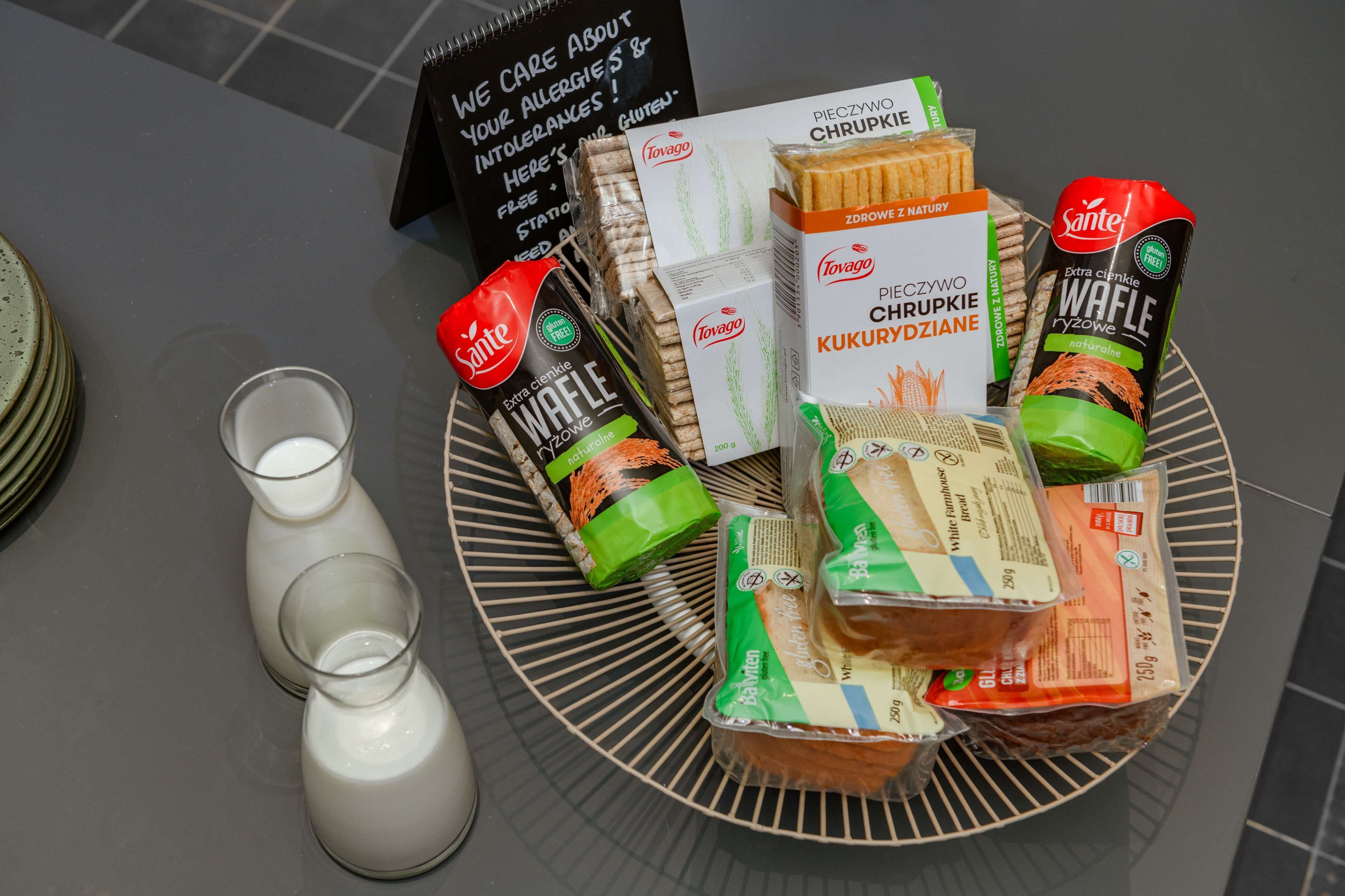 Una mesa con diferentes alimentos, entre ellos aperitivos envasados y pan, además de dos vasos de leche.