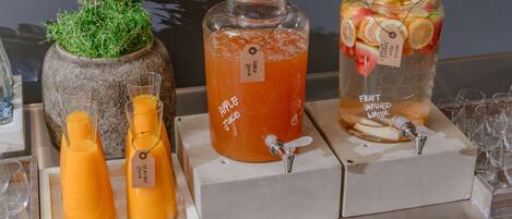 A beverage station with three dispensers: orange juice, apple juice, and fruit-infused water.
