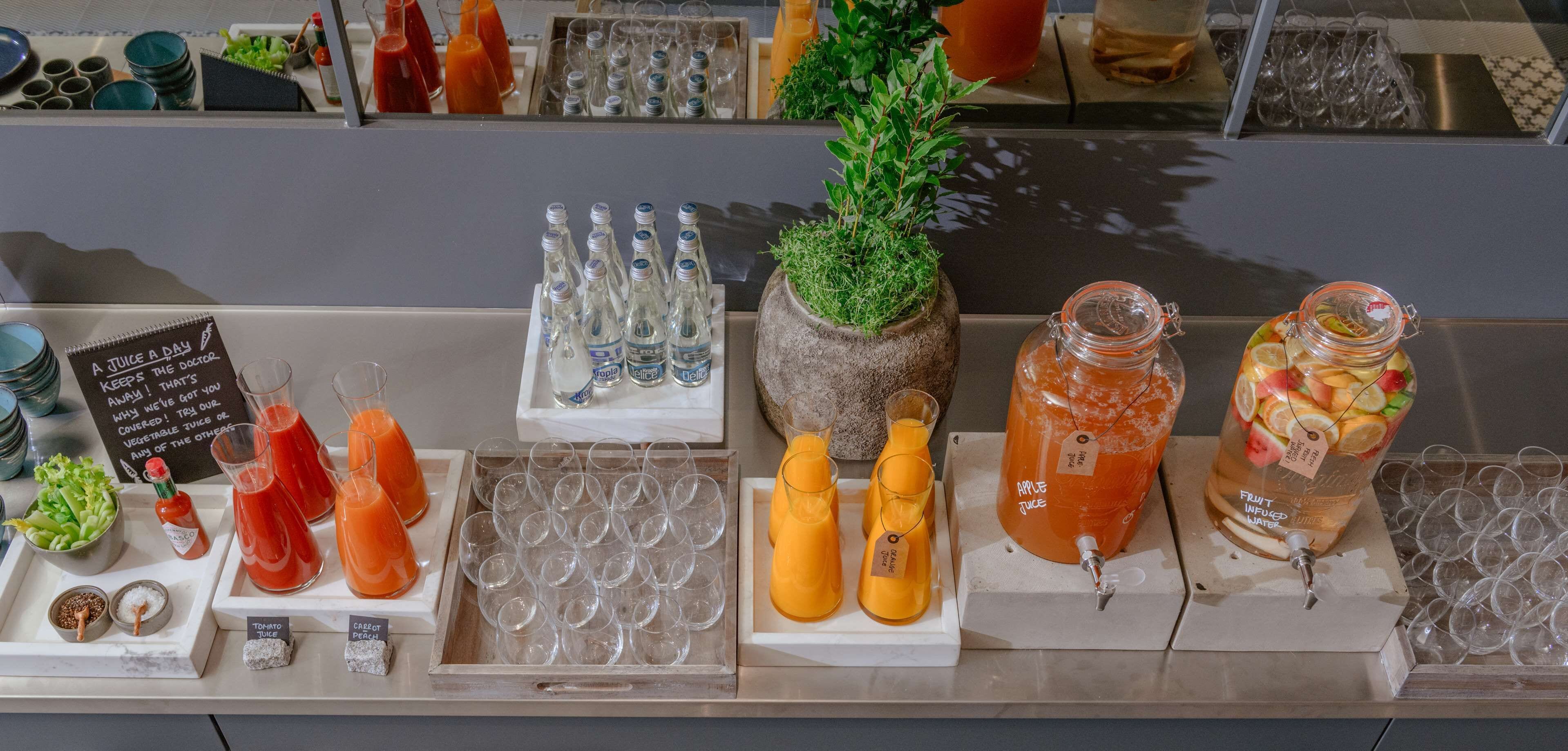 Un bar de zumos con diversas opciones de jugos de frutas, vasos y un cartel que anuncia un zumo diario.
