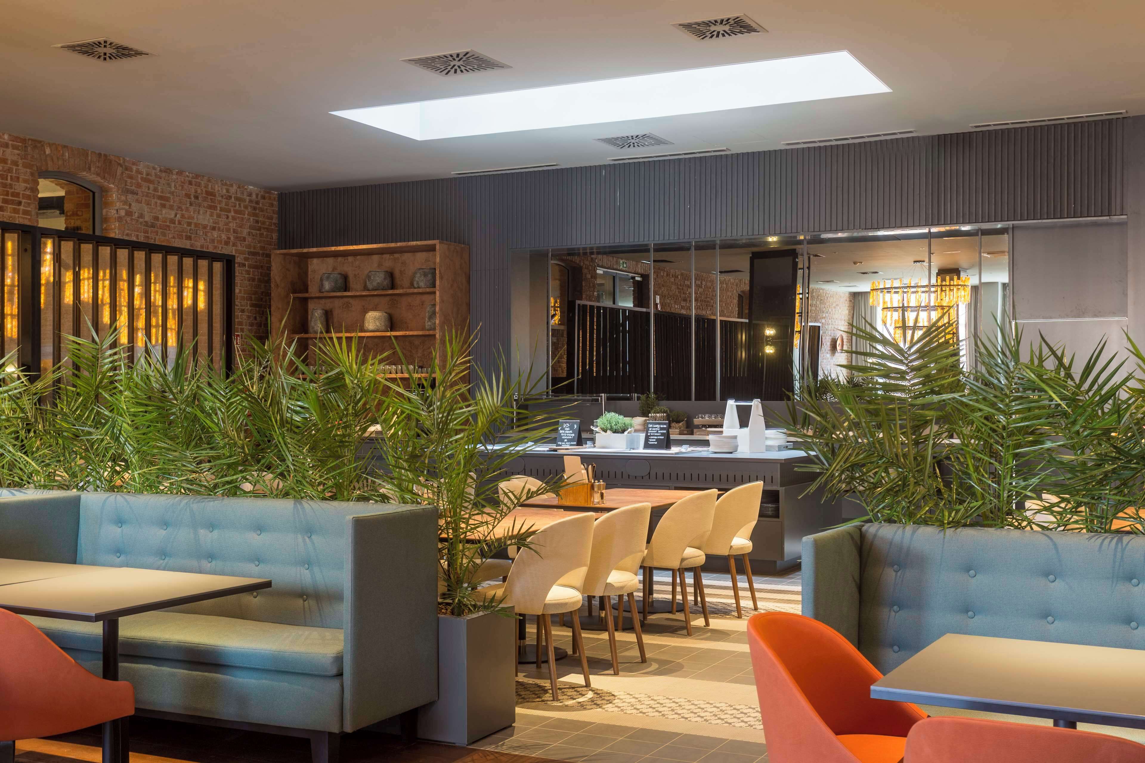 Un espace de détente intérieur moderne, doté de canapés et de fauteuils confortables, d’un comptoir de bar et de plantes en pot.