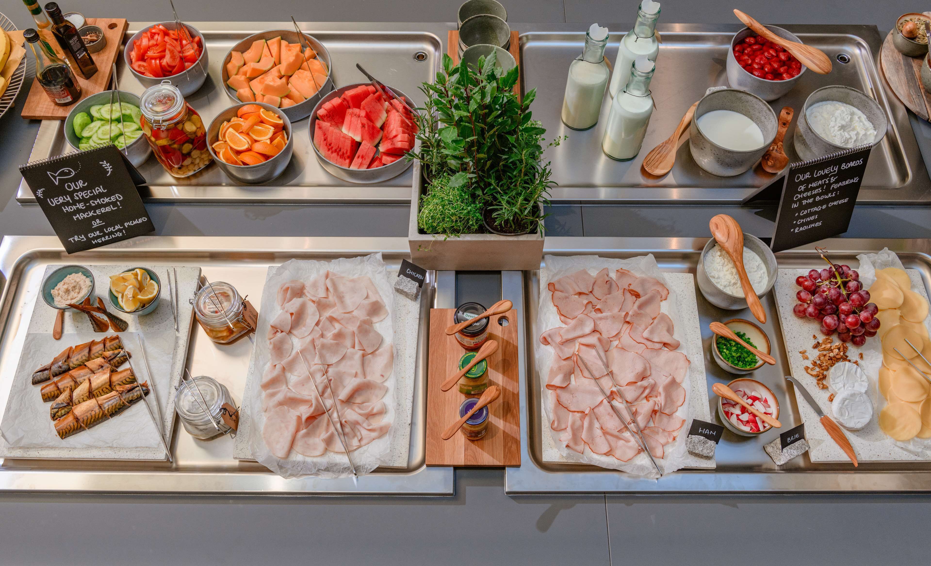 A variety of food items and condiments displayed on trays in a buffet setting.