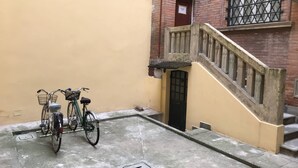 A narrow alleyway with a concrete floor, a wooden staircase, and a brick building with a black door. - Studio Hosts 2 Via Dè Ruini - Flat in Bo (Bologna)