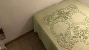 A small, single-bed room with a green patterned bedspread, two windows with curtains, and a small air conditioning unit on the wall. - Studio Hosts 2 Via Dè Ruini - Flat in Bo (Bologna)