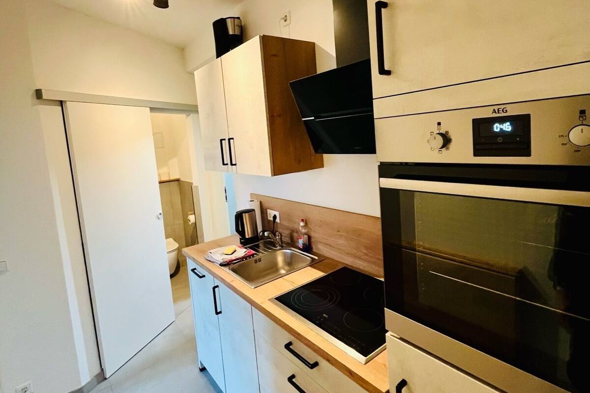 A modern kitchen with white cabinets, a stainless steel sink, a black stove, and an oven.