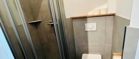 Un baño moderno con ducha acristalada, inodoro y lavabo.