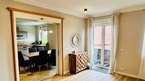 A spacious living area with a dining table and chairs, a wooden cabinet, and a sliding glass door leading to a balcony. - Ferienwohnung Maedchen (Wunstorf)