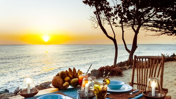 A table set for two with a view of the sunset over the ocean. - Karamba (Kizimkazi)