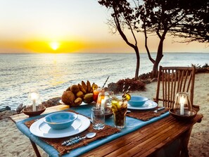 A table set for two with a view of the sunset over the ocean. - Karamba (Kizimkazi)