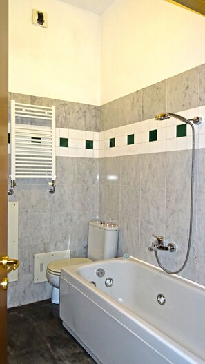 A bathroom with a bathtub, toilet, and a towel rack.