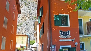 A narrow street with buildings on either side, including a restaurant and a repair center. - Holideal Campione Beach House (Tremosine)