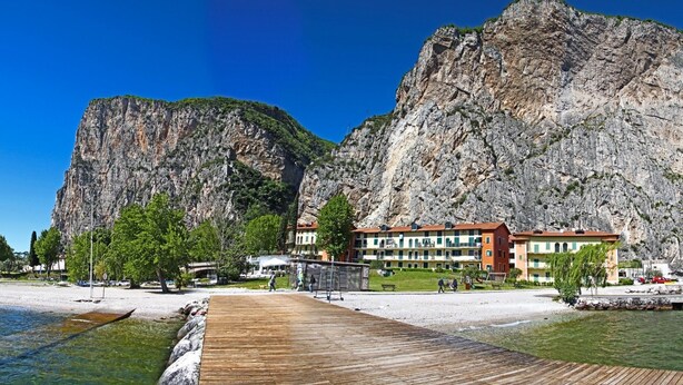 A coastal hotel with a wooden boardwalk leading to the beach, surrounded by rocky cliffs and greenery. - Holideal Campione Beach House (Tremosine)