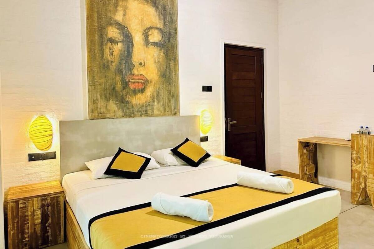 Una habitación de hotel moderna con una cama grande, un cuadro en la pared y una mesita de noche de madera.