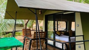 Une petite pièce extérieure fermée, aménagée avec un lit, des meubles en bois et une table verte.