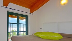 A bedroom with a bed, a window with a view, and a wooden ceiling. - Holideal Campione Bed & Surf (Tremosine)