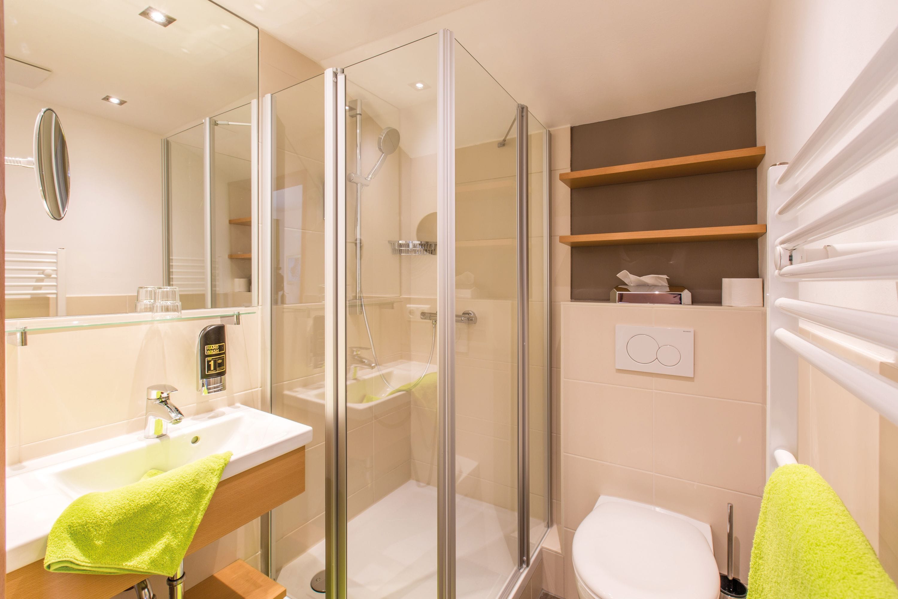 A modern bathroom with a glass-enclosed shower, a white sink, and a toilet.