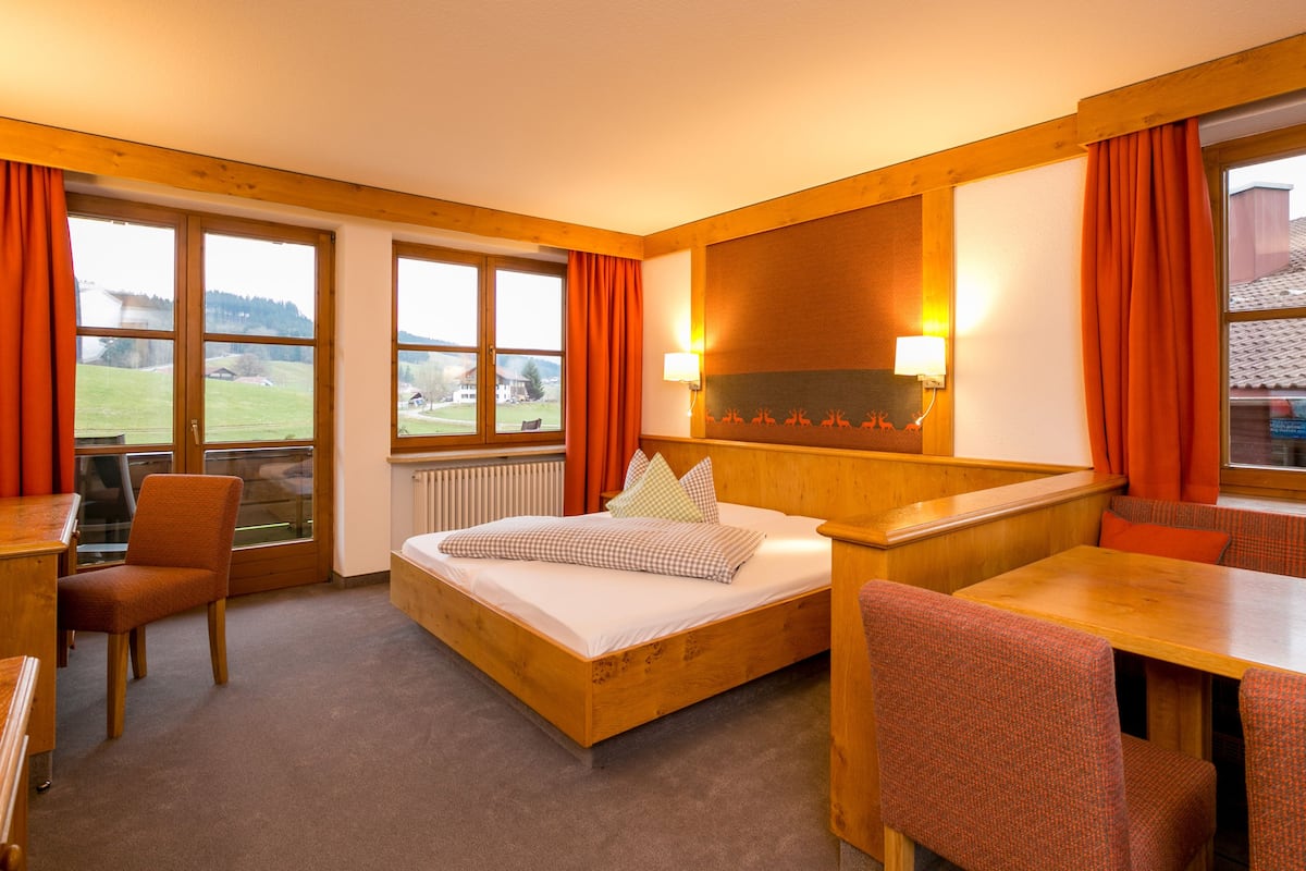 Habitación de hotel con cama, escritorio, silla y vistas al exterior.
