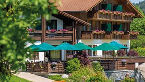 A wooden chalet with balconies, outdoor seating, and green umbrellas.