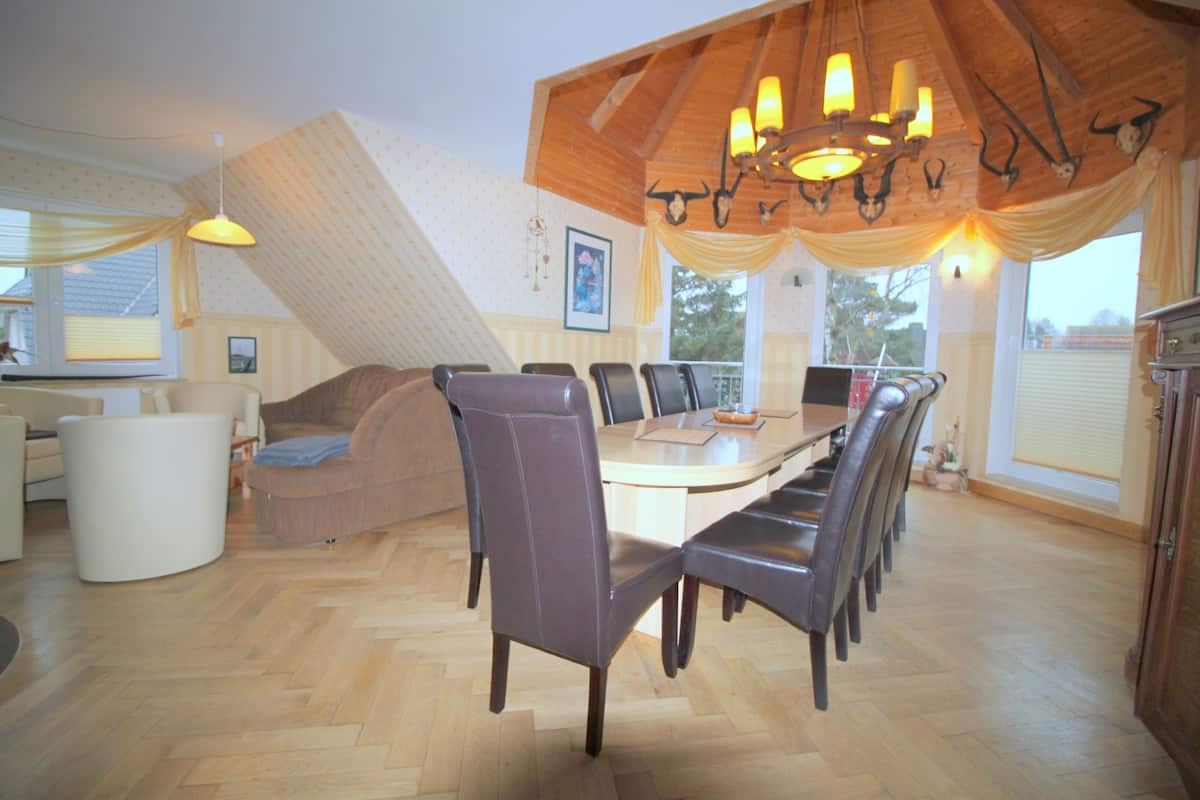 A dining area with a wooden ceiling, a large table, and several chairs.