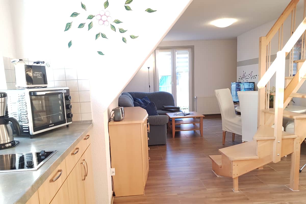 A compact living space with a kitchenette, a sofa, a dining table, and a staircase.