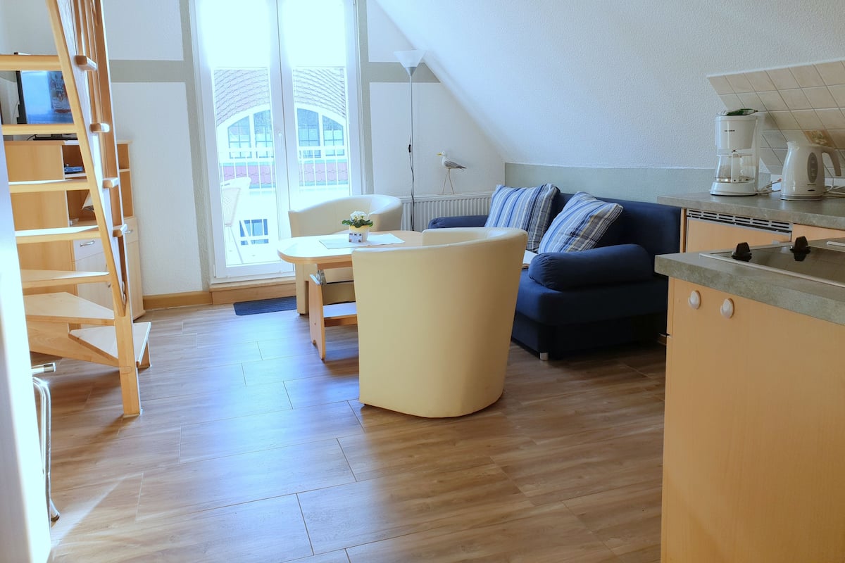 A modern apartment with a loft-style living area, a dining space, and a kitchenette.