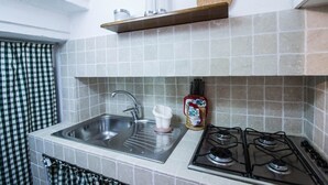 Une cuisine équipée d’un évier, d’une cuisinière et d’une étagère au-dessus de l’évier.