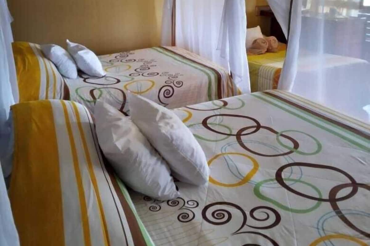 A room with two beds, each with a canopy bedspread and pillows.