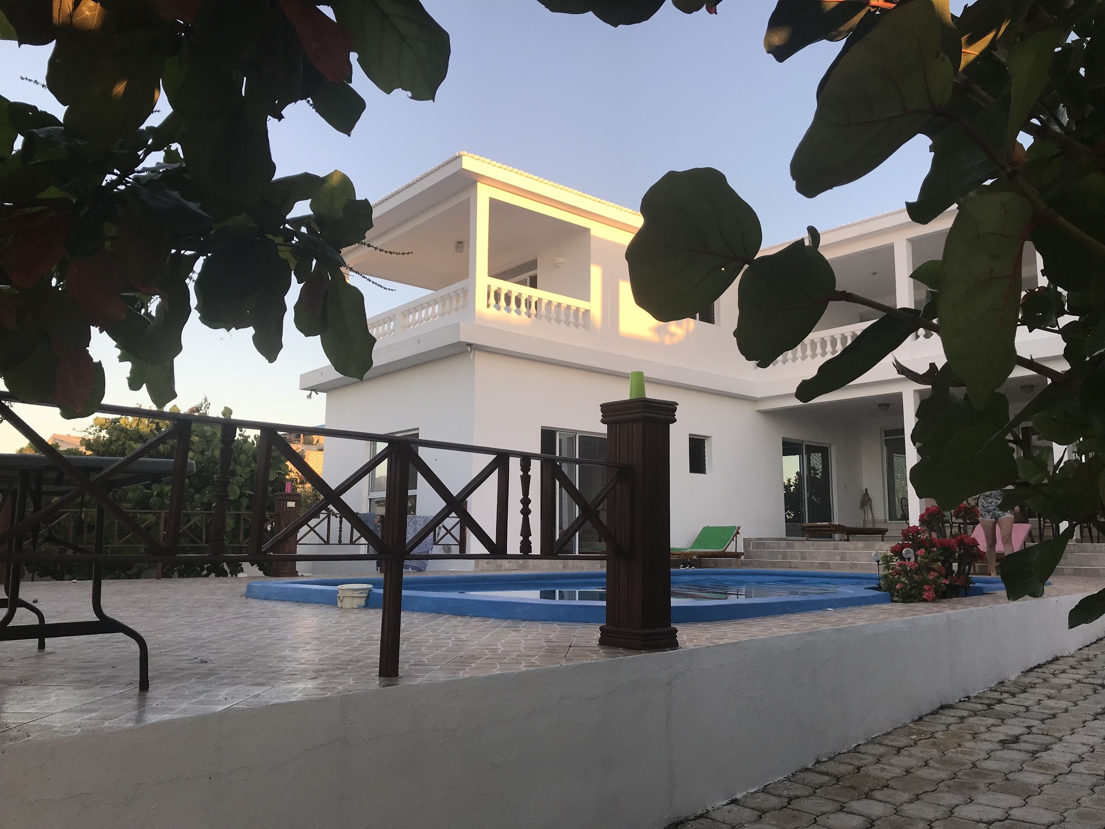Un edificio de dos pisos con balcón, piscina y jardín.