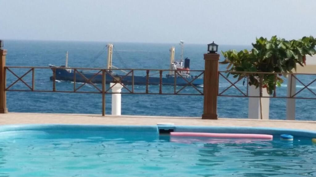 Une piscine offrant une vue sur l’océan et les navires qui se dessinent à l’horizon.