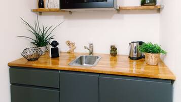 A compact kitchen with a built-in microwave, a sink, and a wooden countertop.