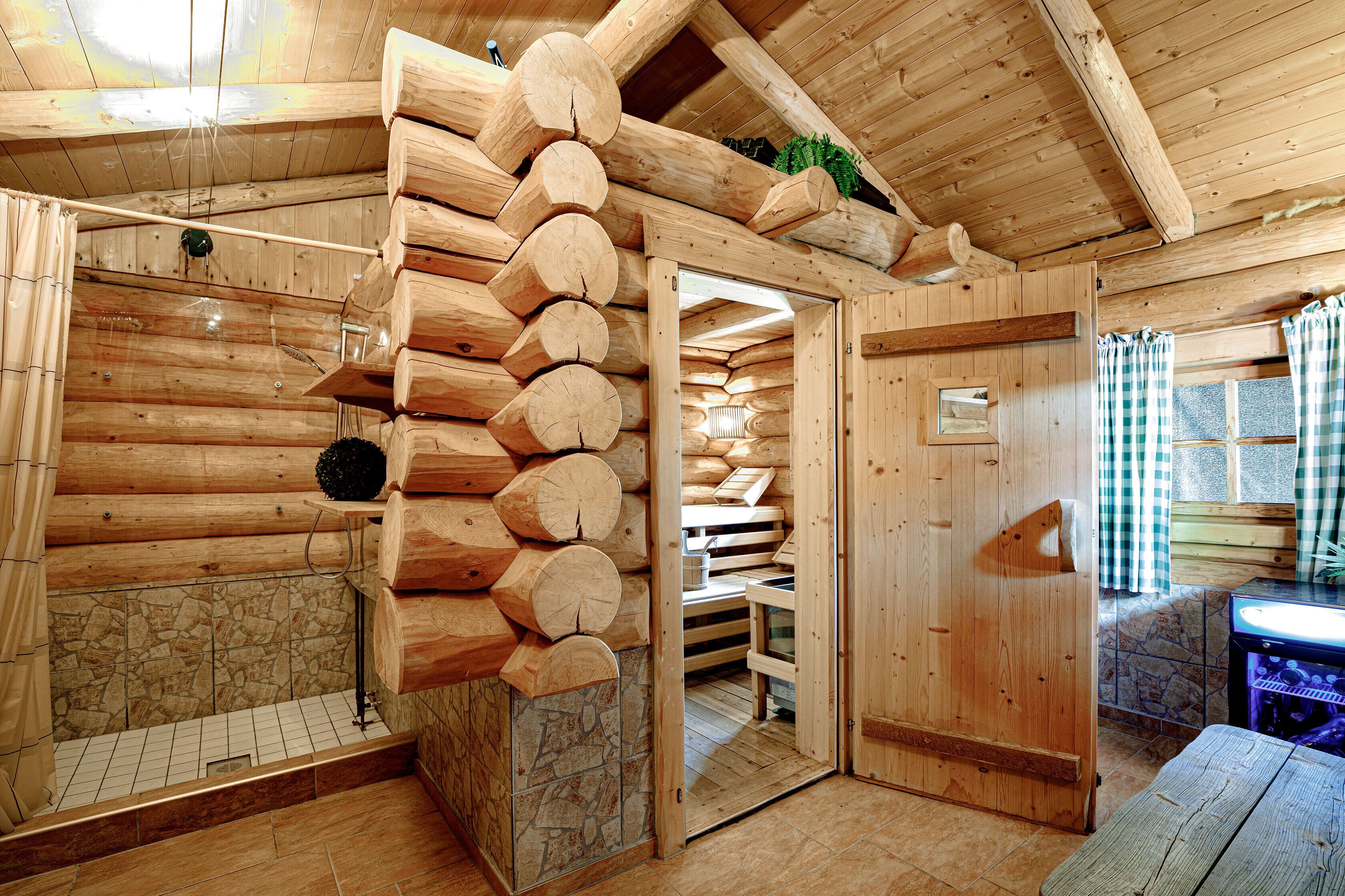 Ein Blockhaus-Interieur mit Kamin aus Stein, einer Wand aus Holzbalken und einer hölzernen Bank.