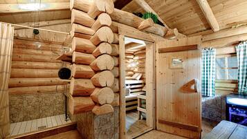 Ein Blockhaus-Interieur mit Kamin aus Stein, einer Wand aus Holzbalken und einer hölzernen Bank.