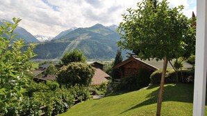 A rural landscape with a wooden cabin, lush greenery, and mountains in the background. - Landhaus Kitzblick (Piesendorf)