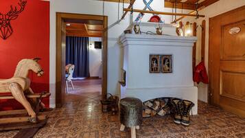 Um interior tradicional com um balanço de madeira, lareira branca com lenha e parede vermelha decorada com um veado.