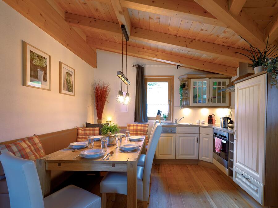 Een gezellige keuken met houten balken, een eettafel gedekt voor vier personen, en een doorkijk naar de aangrenzende eetruimte.