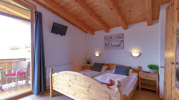 A wooden-framed bedroom with a bed, bedside table, and a small potted plant.