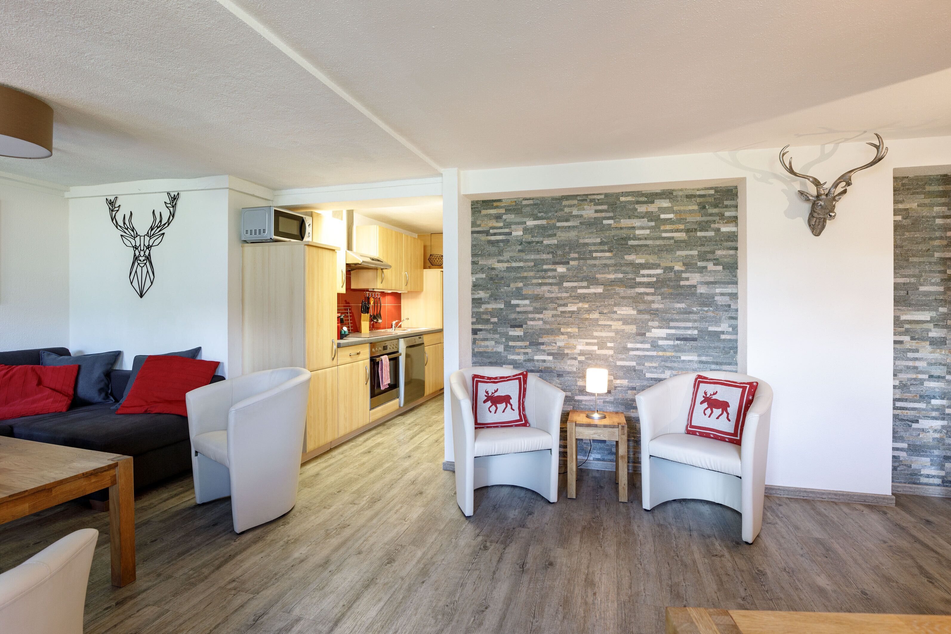 A modern living room with a sofa, two armchairs, a coffee table, and a fireplace with a stone wall.