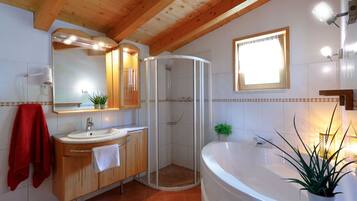 Une salle de bain moderne avec un plafond en bois, une grande baignoire, une douche à parois de verre et un meuble-lavabo avec un miroir.