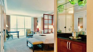 A hotel room with a large bed, a desk, a chair, a dining table, and a kitchen area with cabinets and a countertop. - No Resort Fee | Strip Views, Pools & Parking (Las Vegas)
