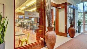 A modern interior with a reception area, large vases, and a dining area visible through the glass. - No Resort Fee | Strip Views, Pools & Parking (Las Vegas)