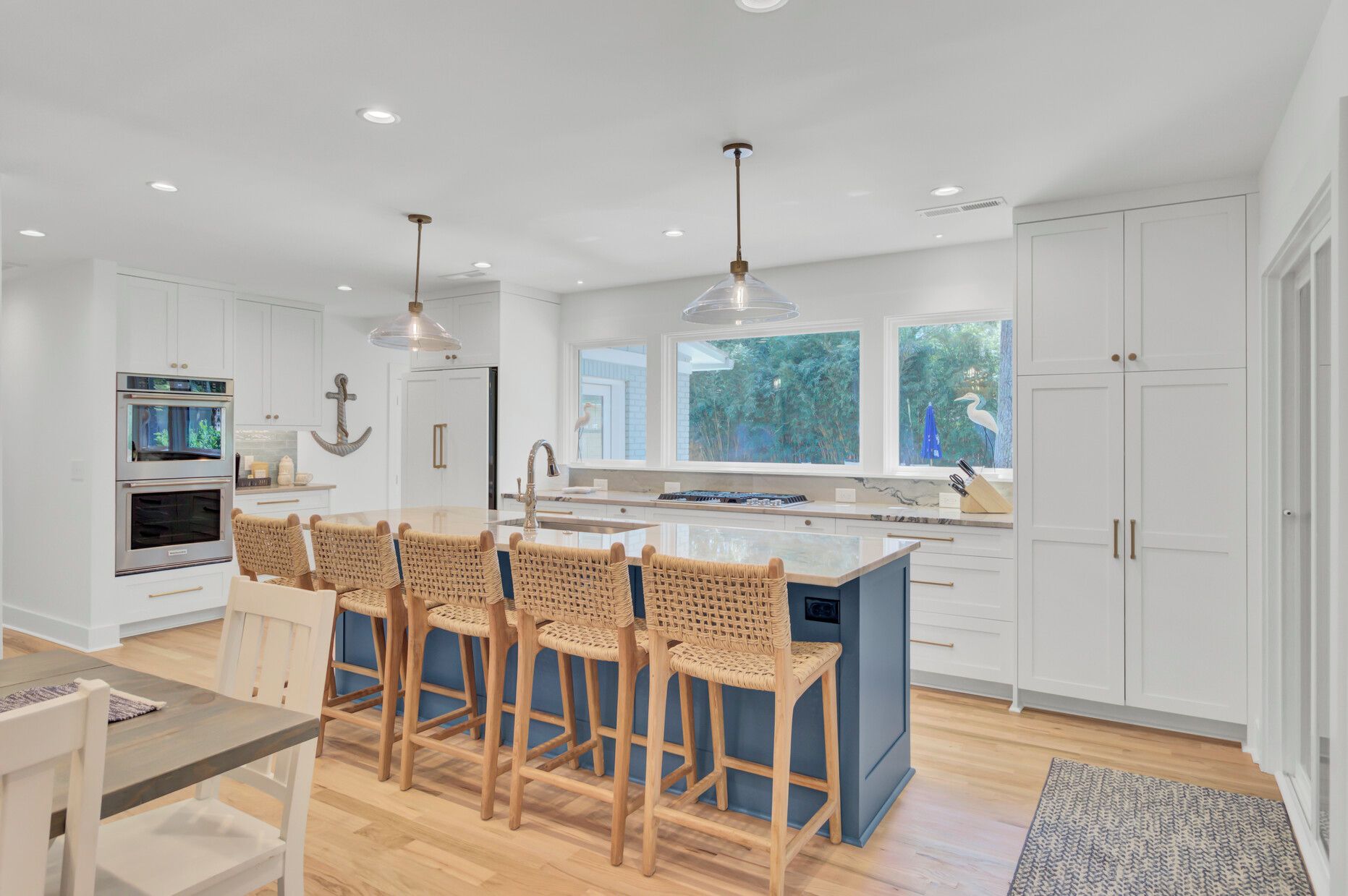 A modern kitchen with a central island, bar stools, and a dining area.