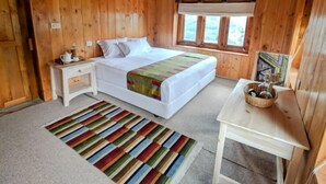 A wooden cabin bedroom with a bed, nightstand, table, and window. - Kyirmu Lodge Phaplu (Phaplu)