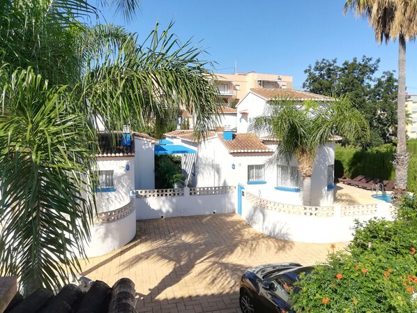 Zona residencial con entrada porticada, piscina y un coche estacionado.