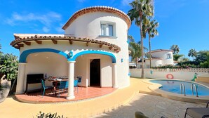 A villa with a pool, outdoor seating, and a covered patio.