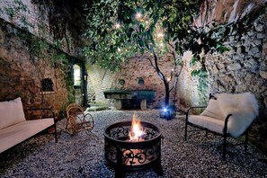 An outdoor seating area with a fire pit, stone walls, and a rustic ambiance. - Palazzetto of the 600 with suggestive private garden, in the heart of Rome (Roma)