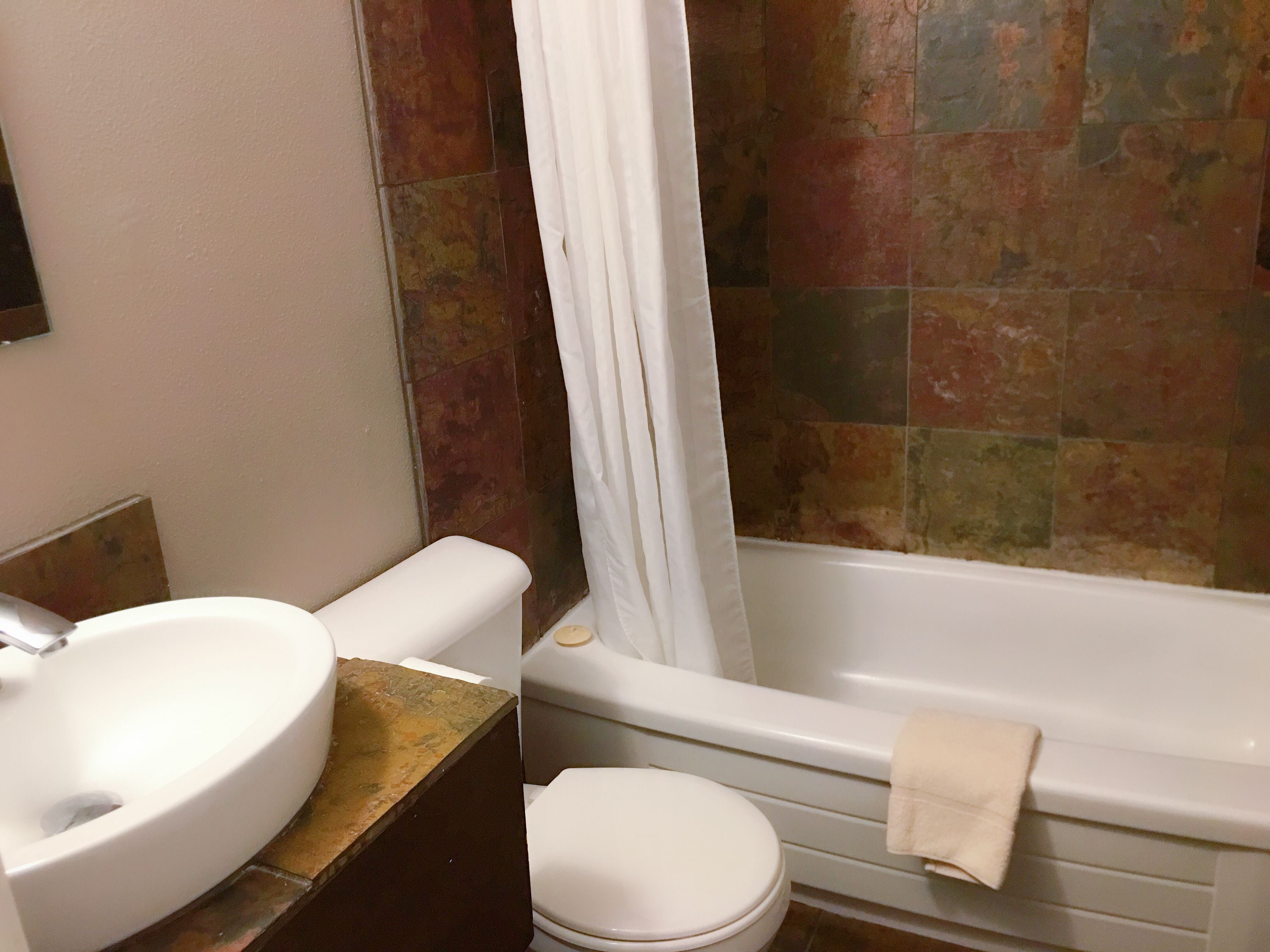 Une salle de bain avec un lavabo, des toilettes et une baignoire, le tout de couleur blanche.