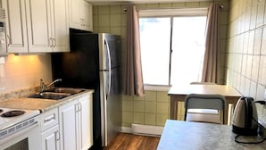 A compact kitchen with white cabinets, a black refrigerator, a sink, and a countertop.