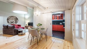 Ein modernes Wohnzimmer mit Esstisch, einem roten Sofa und einer Küche mit roten Schränken.