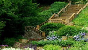 A stone staircase with wooden railings, surrounded by lush greenery and flowering plants. - Gorgeous Village Barn, nr Banbury / Chipping Norton - Cotswolds, Oxfordshire (Shutford)
