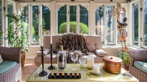 A conservatory with a high ceiling, large windows, and a cozy seating area with a sofa and armchairs. - Gorgeous Village Barn, nr Banbury / Chipping Norton - Cotswolds, Oxfordshire (Shutford)